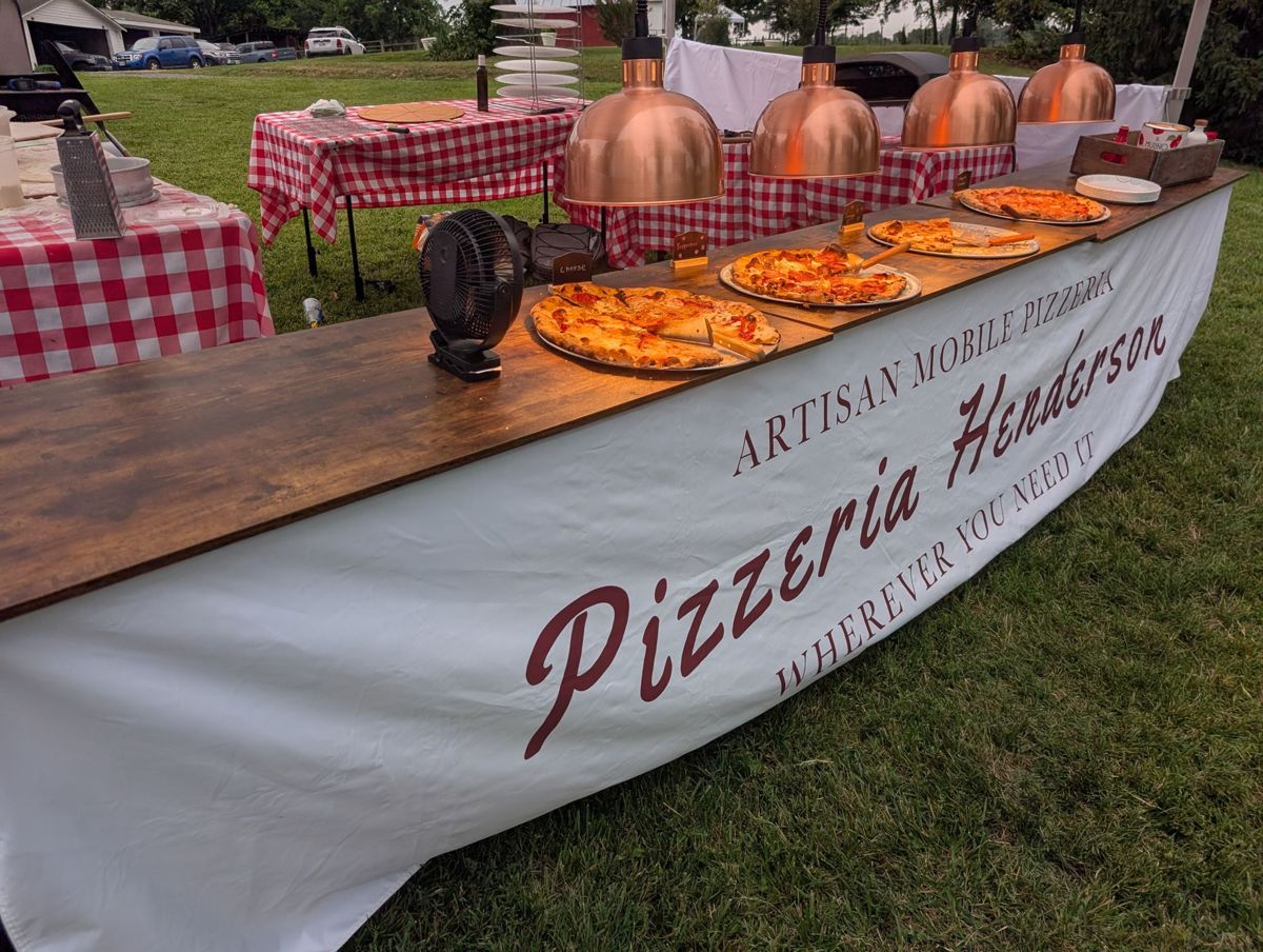 Pizzas on the serving counter under copper warming lamps