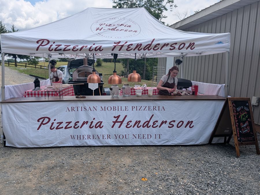 Pizzeria Henderson tent, copper warming lamps, and oven set up with the crew at work