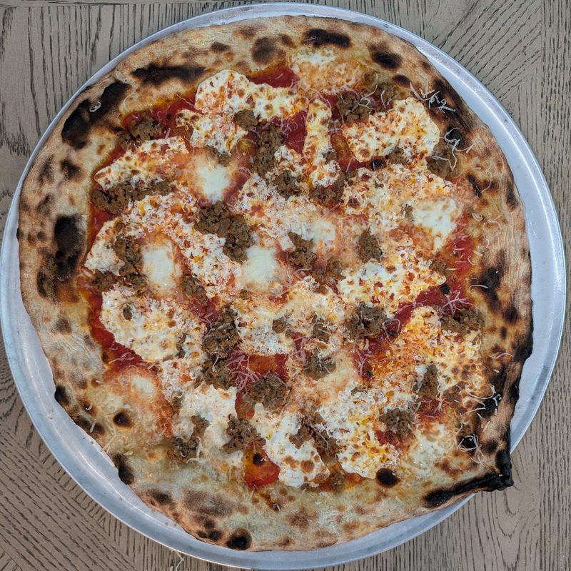Spicy Italian sausage pizza with handmade mozzarella and a charred crust